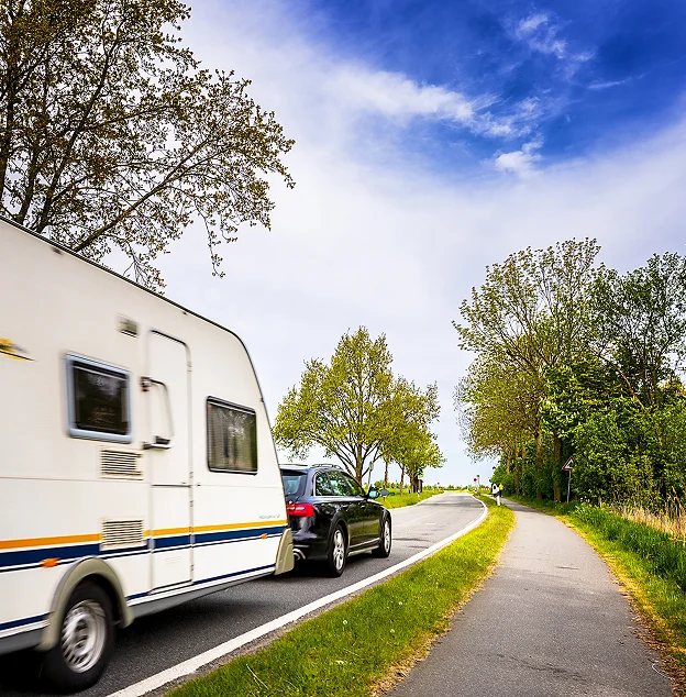 Voiture noire tractant une caravane blanche sur une route de campagne bordée d'arbres à Vineuil près de Blois dans le Loir-et-Cher 41